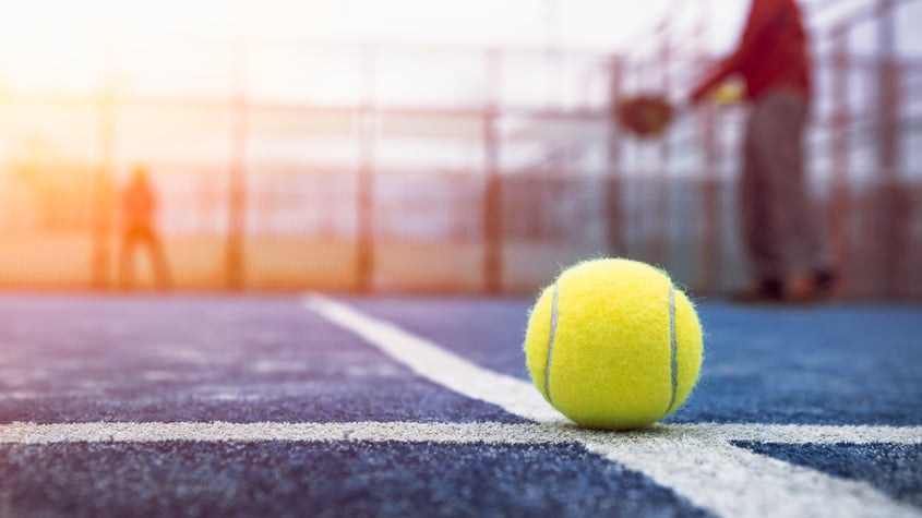 Yellow Ball on Floor behind Paddle Net in Blue Court Outdoors. Padel Tennis