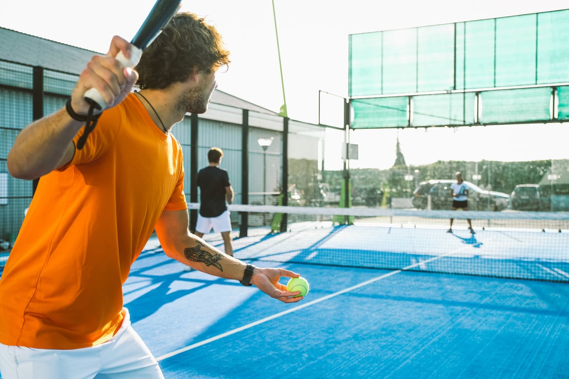 Mixed padel match in a blue grass padel court -  Beautiful girl and handsome man playing padel outdoor